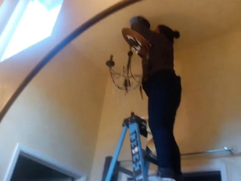 Electrician installing a chandelier in a Escanaba residence